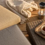 Salon de jardin cocooning : coussins et plaid sur table d’extérieur pour soirées confort